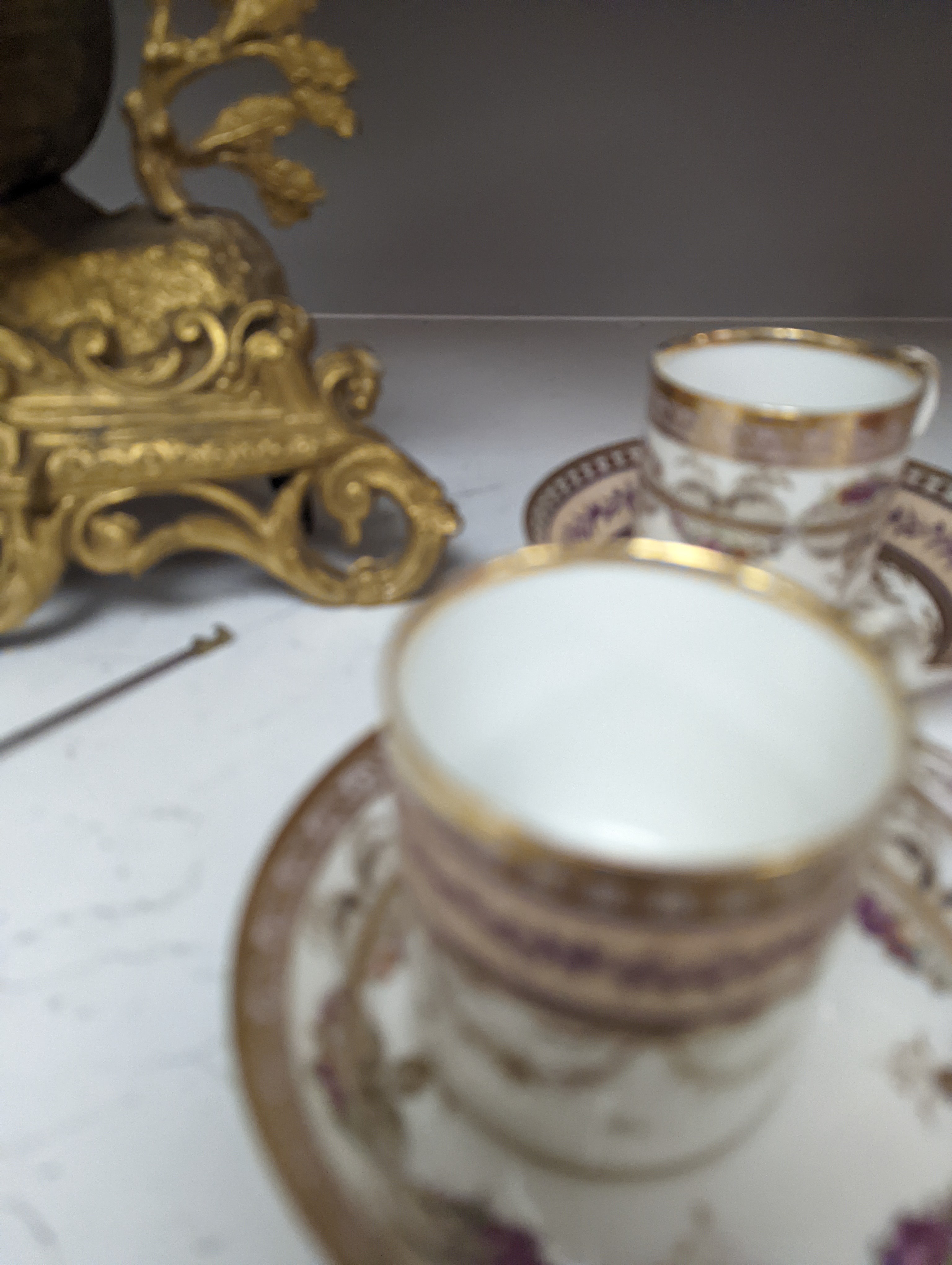 A Duc d'Angouleme coffee can and saucer painted with a puce chain of leaves on a salmon coloured ground and another painted with a flower chain, black feather and a gilt line, latter with stencilled red mark 'Manuf de M